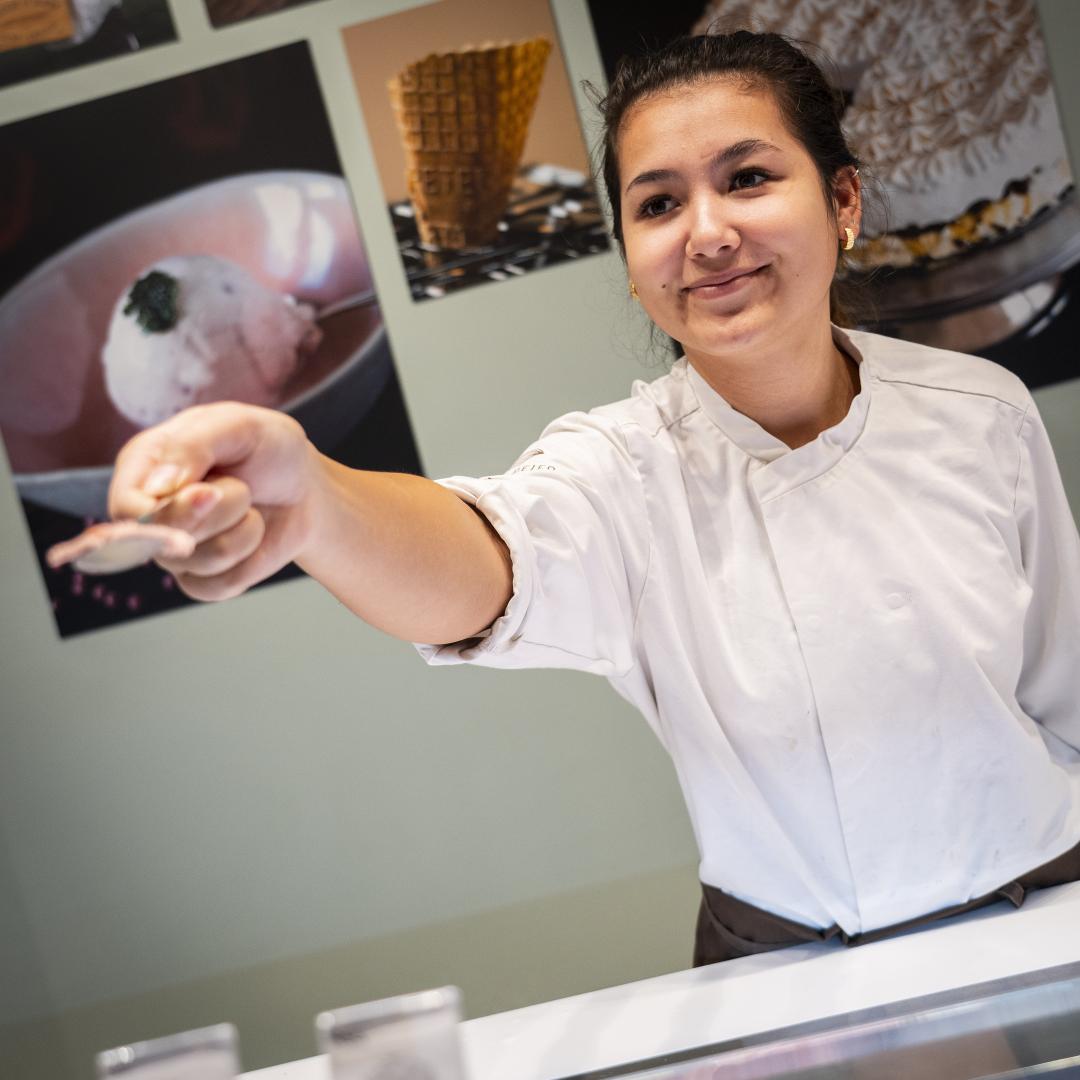 En sød medarbejder som deler en smagsprøve ud til en kunde